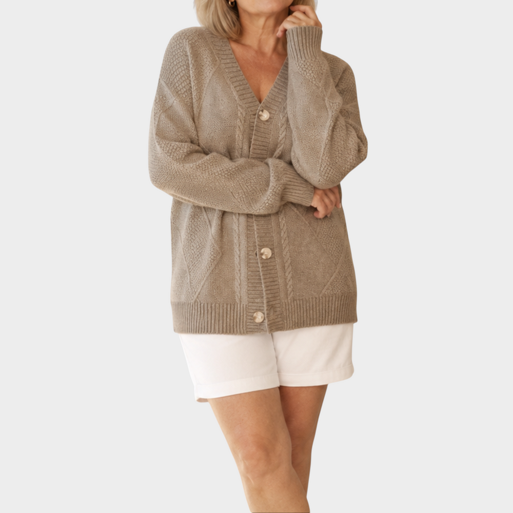 Zane & Inese Pauline beige knitted cardigan with V-neck, button-up front, and ribbed cuffs worn with white shorts.