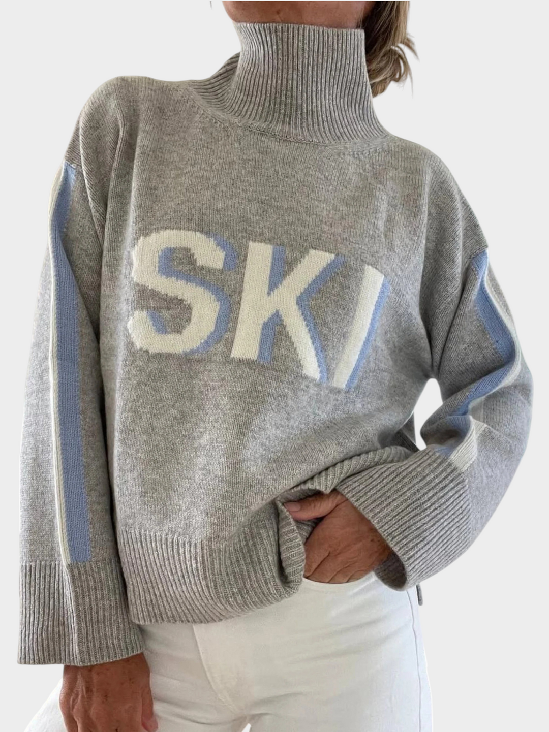 Zane & Inese grey retro knit sweater with high collar, SKI lettering, and blue side stripes on sleeves.