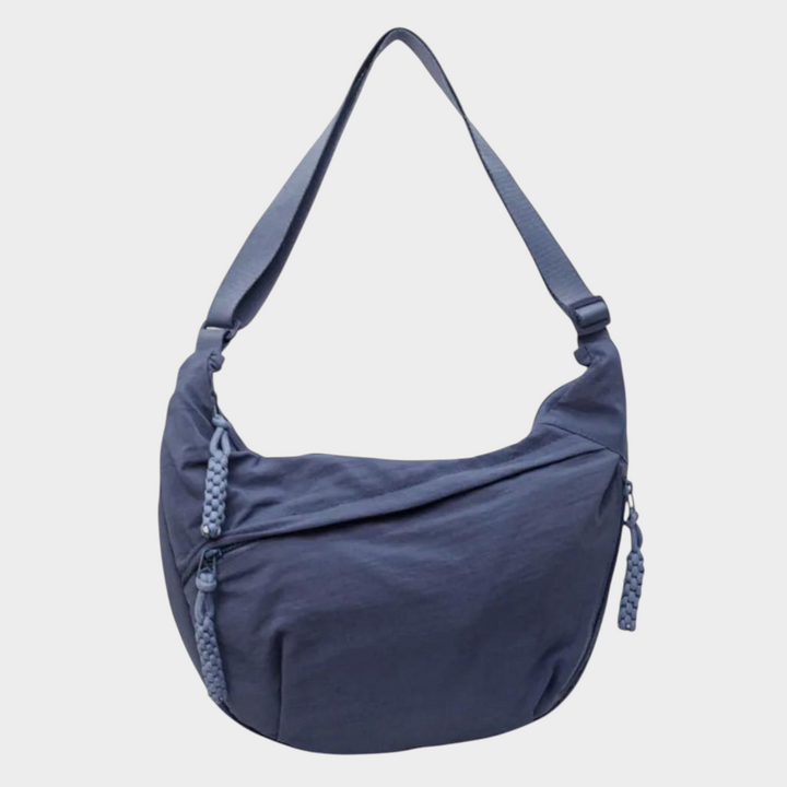 Zane & Inese Serafīna blue nylon crescent shoulder bag with adjustable strap and practical zipper compartments.