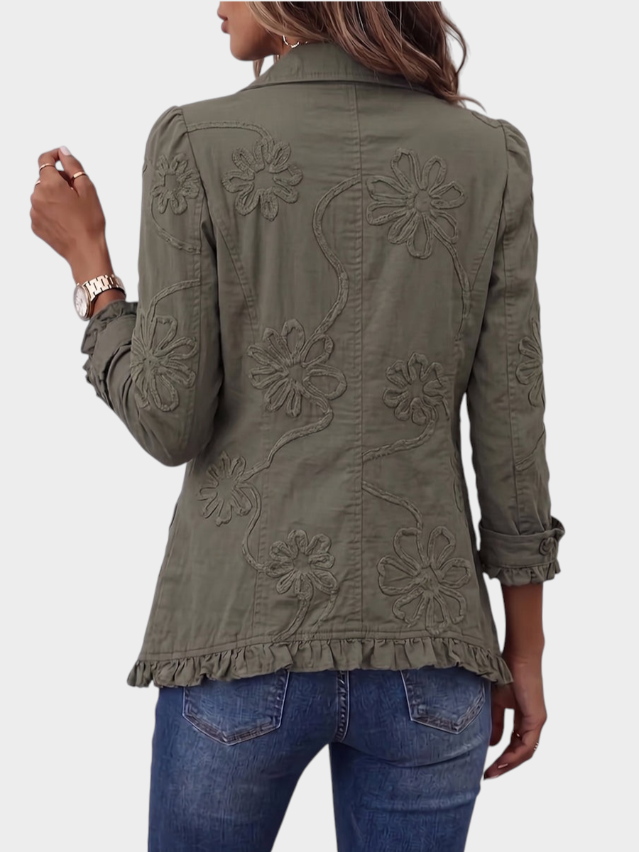 Zane & Inese Vaidelote olive green utility jacket with floral embroidery, ruffled hem, and collar, worn from behind.