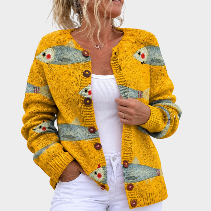 Zane & Inese golden yellow knit cardigan with a whimsical fish pattern and round buttons worn by a woman.