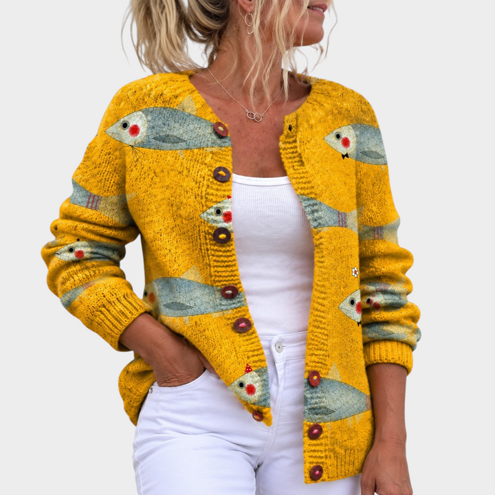 Zane & Inese golden yellow knit cardigan featuring a whimsical fish pattern and round buttons worn over a white top.
